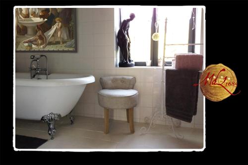 a bathroom with a tub and a chair and a sink at Manoir de Livet in Saint-Germain-de-Livet