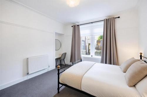 a bedroom with a bed and a window at Coastal Nest - Cosy flat in Irvine town centre - 5 minute drive from beach in Irvine