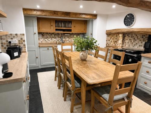 a kitchen with a wooden table and chairs at April Cottage in Hordle