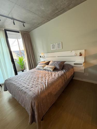 a bedroom with a large bed and a large window at Petit BANFIELD in Banfield