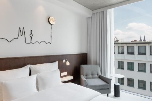 ein Schlafzimmer mit einem Bett, einem Stuhl und einem Fenster in der Unterkunft Ruby Ella Hotel Cologne by IHG in Köln