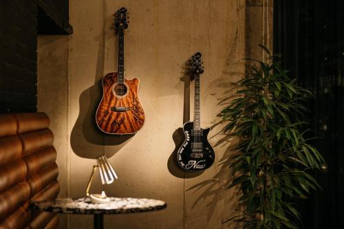 Zwei Gitarren hängen an einer Wand neben einem Tisch. in der Unterkunft Ruby Ella Hotel Cologne by IHG in Köln