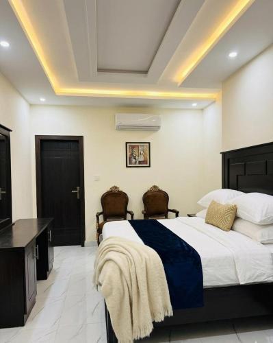 a bedroom with a large bed and two chairs at Mak Palace Hotel in Sialkot