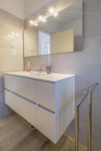 a white bathroom with a sink and a mirror at Vila Vista Luz in Lagos
