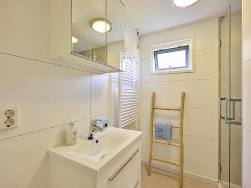 a white bathroom with a sink and a mirror at Chalet Sea Birds in Goedereede