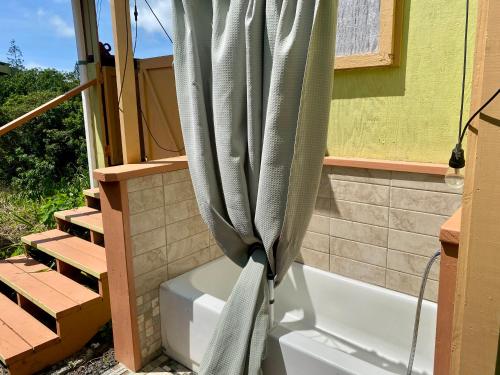 a shower curtain in a bathroom next to a tub at Artsy Cabin on Organic Farm in Naalehu