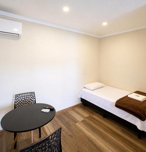 a small room with a bed and a table at Lá Casa do Manguinha in Guarulhos
