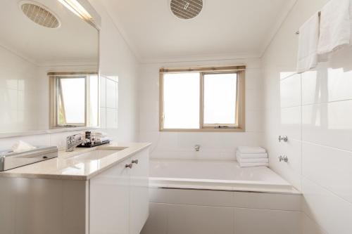 a white bathroom with a tub and a sink at Harrigan's Hunter Valley in Pokolbin