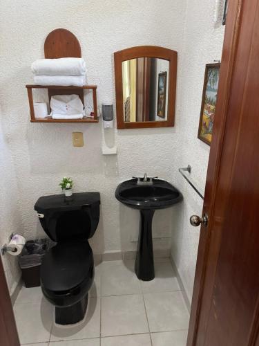 a bathroom with a black toilet and a sink at Villas Mercedes in Zihuatanejo
