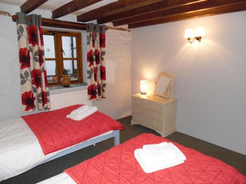 a bedroom with two beds and a window at Primrose Cottage in North Petherwin