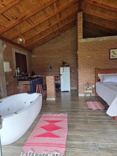 a room with a bath tub and a bed at Chalé Água Santa in São Thomé das Letras