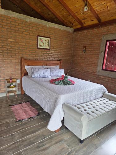 a bedroom with a large bed and a couch at Chalé Água Santa in São Thomé das Letras