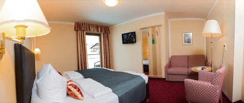 a hotel room with a bed and a chair at Hotel Schneeberger in Niederau