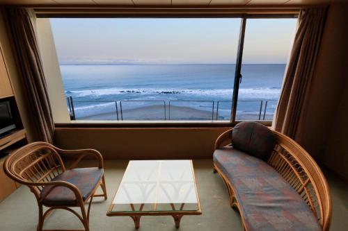 a living room with a couch and chairs and a large window at Wakamatsu Hot Spring Resort in Hakodate