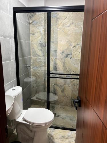 a bathroom with a toilet and a glass shower at Hotel Provenza Suites in Ocaña