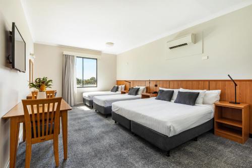 a hotel room with two beds and a desk at Metro Hotel Perth City in Perth