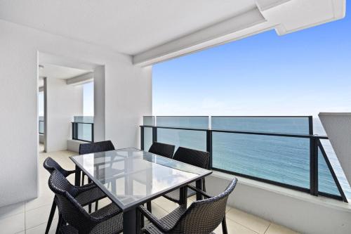 a dining room with a glass table and chairs at Soul Beachfront Apartments - HR Surfers Paradise in Gold Coast