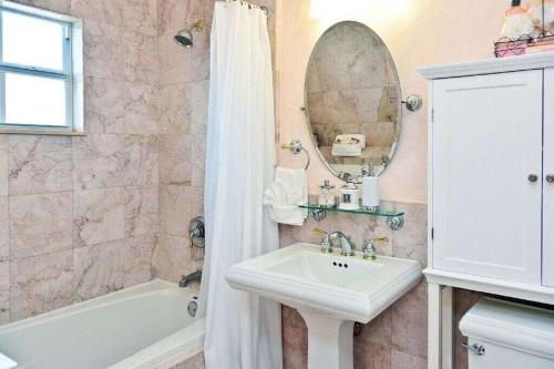 a bathroom with a sink and a tub and a mirror at Casa de David from the 1920s Era in West Palm Beach