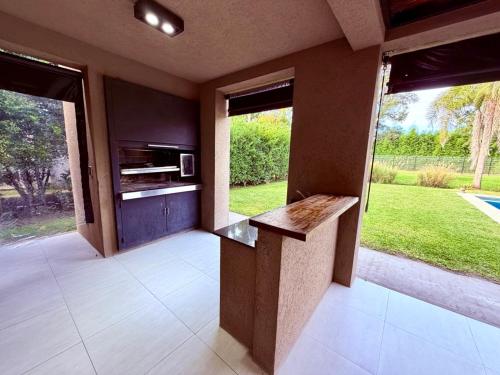 a kitchen with a counter and two large windows at Casa con piscina en Estancias del Pilar, 3 dormitorios, jardín y parrilla in Pilar