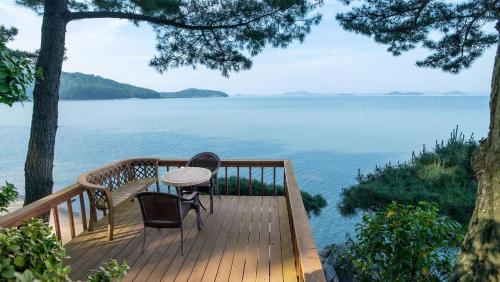 a wooden deck with a table and chairs on the water at Taean Supsogui Bada Pension in Panggal-li