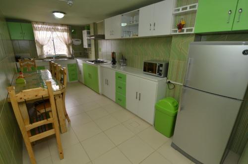 a kitchen with green cabinets and a white refrigerator at Almudena Apart Hotel in La Paz