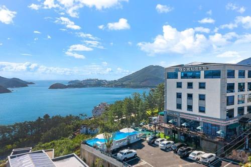 a hotel with a parking lot next to a body of water at Oceanview Spa Beach Resort Yeosu in Yeosu