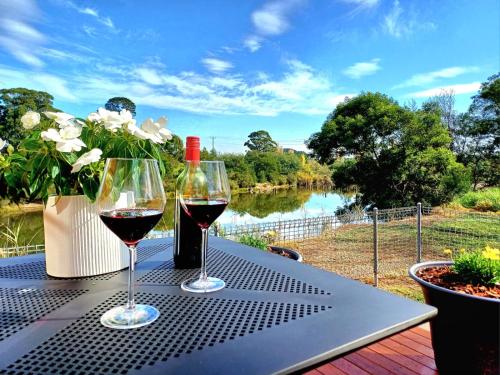 two glasses of wine on a table with a view of a river at BIG4 Stratford Caravan Park in Stratford