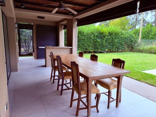 a wooden table and chairs on a patio at Casa con piscina en Estancias del Pilar, 3 dormitorios, jardín y parrilla in Pilar
