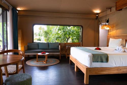 a bedroom with a bed and a couch and a table at Serenity Sands Island Glamping in Bounty Island