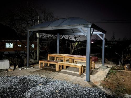 a wooden picnic table under a gazebo at night at Nonsan Yeoyurowa Pension in Nonsan