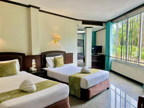 ein Hotelzimmer mit zwei Betten und einem Fenster in der Unterkunft Green House Hotel in Krabi