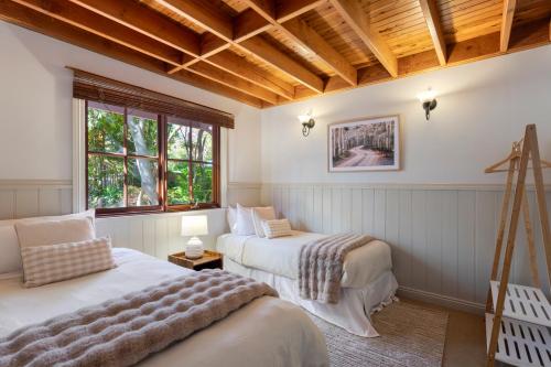 a bedroom with two beds and a wooden ceiling at Leura Lodge in Leura
