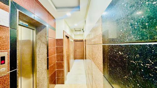 a corridor of a bathroom with brown tiles at Half Moon Grand in Chennai