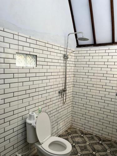 a bathroom with a toilet and a white brick wall at Honey Home in Kuta Lombok