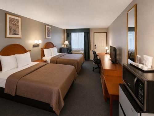 a hotel room with two beds and a desk at Ozark Inn & Suites in Ozark