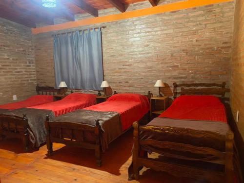 a bedroom with three beds and a brick wall at Cabañas Frago in Villa Amancay