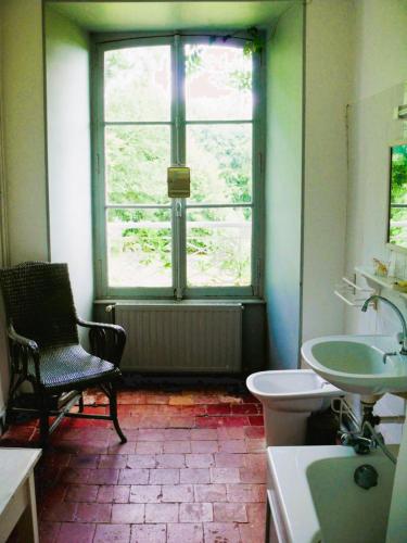 a bathroom with a window and a sink and a chair at Manoir de Pincelu in La Courbe