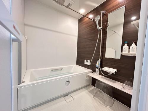 a bathroom with a bath tub and a sink at 南アルプスを望むサウナ付き宿,田園風景,全室エアコン,バーベキュー可 in Hokuto