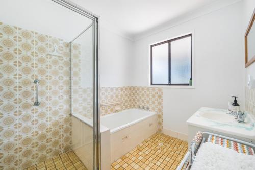 a bathroom with a shower and a tub and a sink at Mirrabooka in Lake Cathie