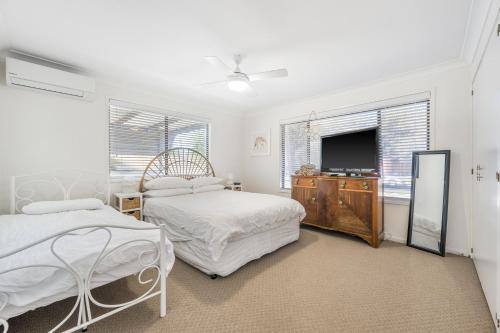 a bedroom with two beds and a flat screen tv at Mirrabooka in Lake Cathie