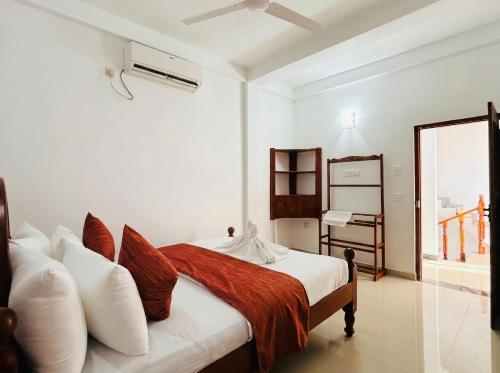a white bedroom with a bed with red and white pillows at Villa Dream D in Hikkaduwa