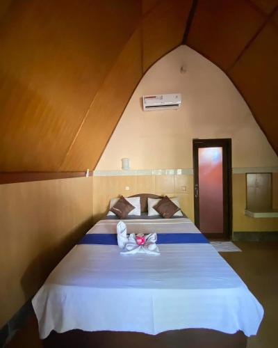 a bedroom with a large bed with two white shoes on it at meno smile cottages 2 in Gili Meno