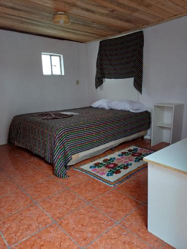 a bedroom with a bed with a window and a rug at Hotel casa de doña Rome in Chichicastenango