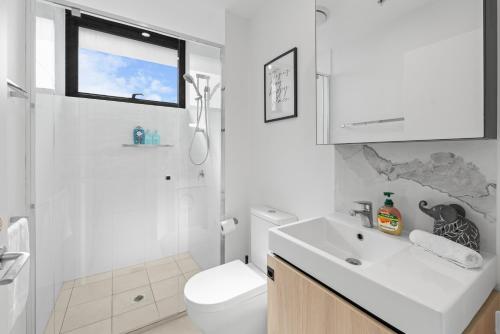 a white bathroom with a toilet and a sink at Brisbane Skyline View 2Beds River view Apt in Brisbane