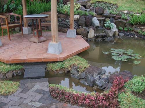 a garden with a pond and a table and a wooden bridge at Strawberry Hill Hotel & Restaurant in Bedugul