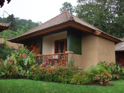 a small house with a balcony in a yard at Strawberry Hill Hotel & Restaurant in Bedugul