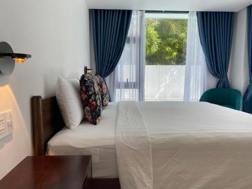 a bedroom with a bed and a window with blue curtains at Sunrise Beach House 1 in Tiến Thành