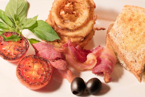 a plate of food with bacon and bread and tomatoes at Gangga Island Resort & Spa in Serai