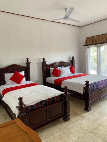 a bedroom with two beds with red pillows at Double One Villas in Amed