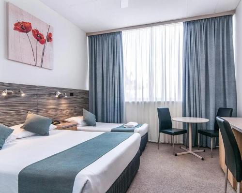 a hotel room with two beds and a table at Comfort Inn Regal Park in Adelaide